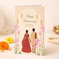 Happy Anniversary card - cream card featuring an illustrated South Asian couple walking hand-in-hand through a lotus garden with lanterns and a golden ornamental arch.
